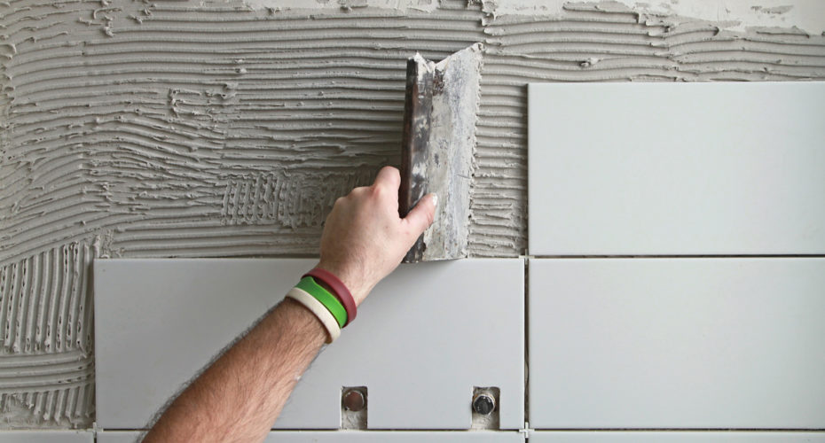 A hand applying bathroom tile.