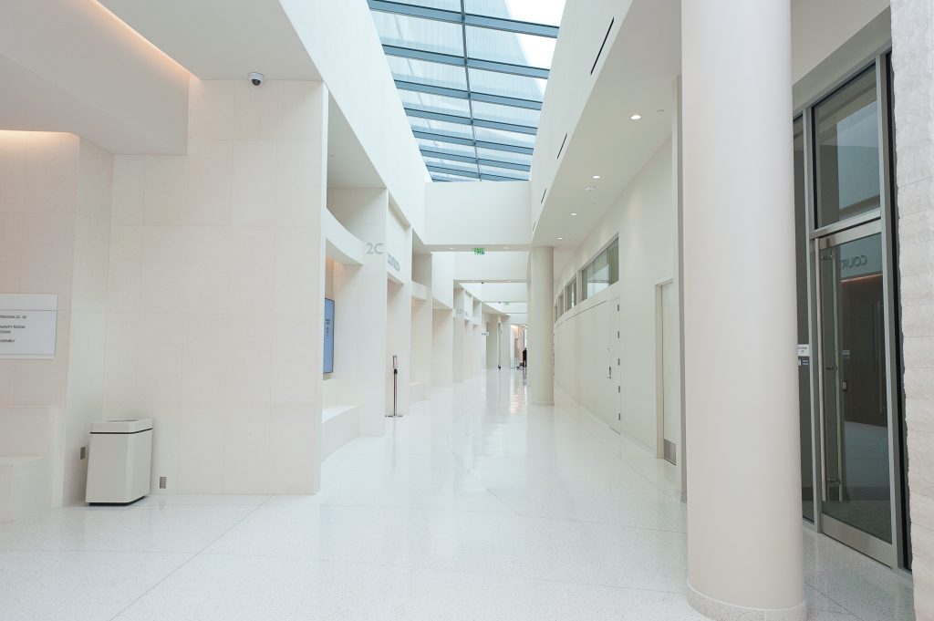 Image of a bright white hallway with light shining through the windows at the top of the ceiling.