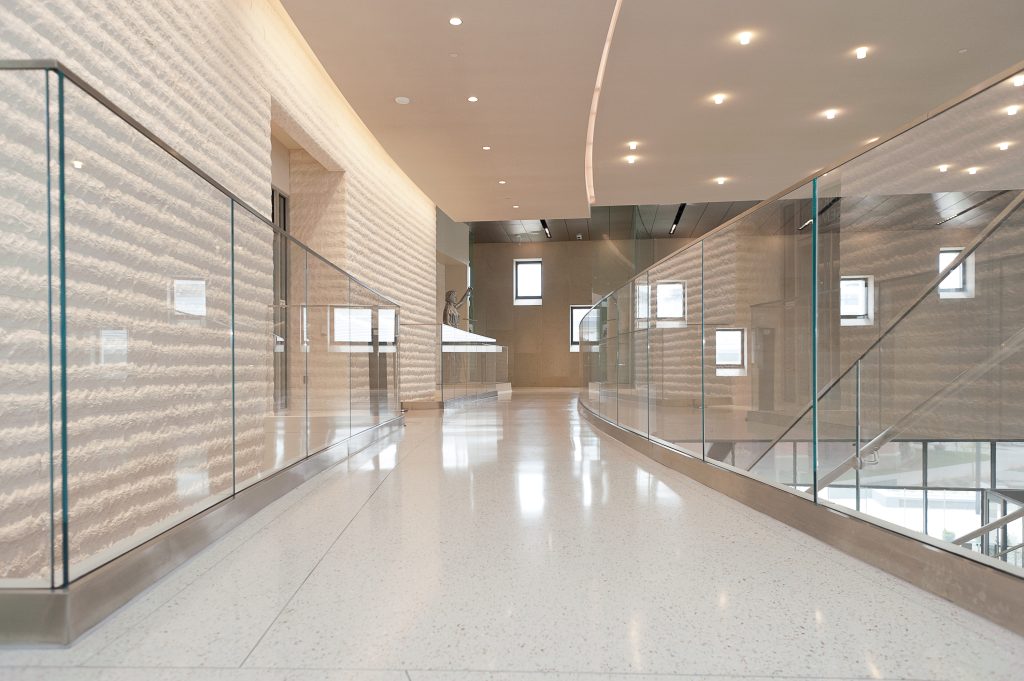 Close up image of a glossy white speckled floor with the glass walls on the left and right.