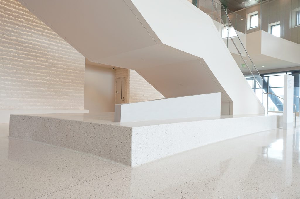 Close up image of a shiny white speckled floor and back part of stairs.