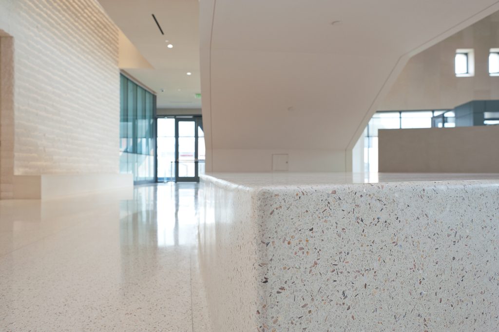 Close up image of a shiny white speckled floor and back part of stairs.