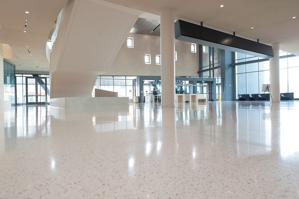 Image of a shiny white speckled floor close up with the back of the stairs and entrance of the building in the far left and right.